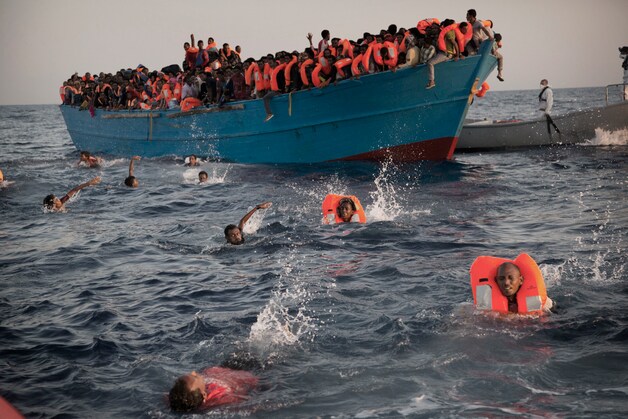 Migranten springen uit een overbevolkte boot op de Middellandse Zee terwijl ze gered worden door een ngo op 29 augustus 2016.