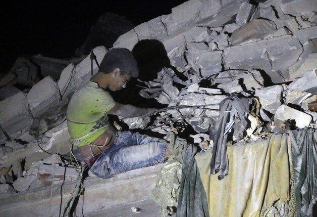 Een Syrische jongen zit vast in het puin nadat een gebouw werd geraakt door een luchtaanval en wacht tot hij kan bevrijd worden.