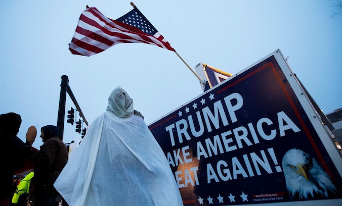 Een demonstrant met een imitatiegewaad van de KKK bij een Trump-bijeenkomst