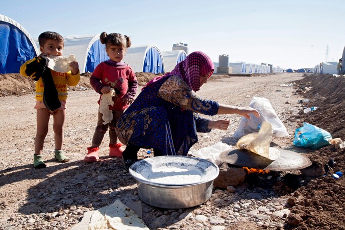 Een uit Mosoel gevluchte vrouw bakt brood voor kinderen in het opvangkamp in Khazir.