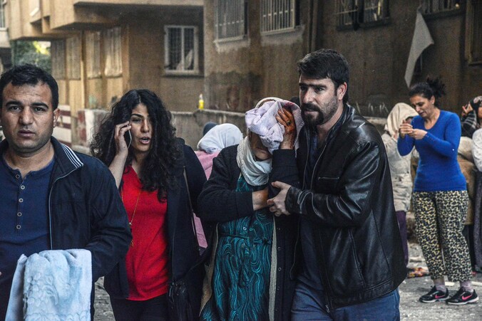 Inwoners van Diyarbakir begeleiden een vrouw die gewond is geraakt bij een explosie in de zuidoostelijke stad, waar ook parlementariërs zijn gearresteerd.
