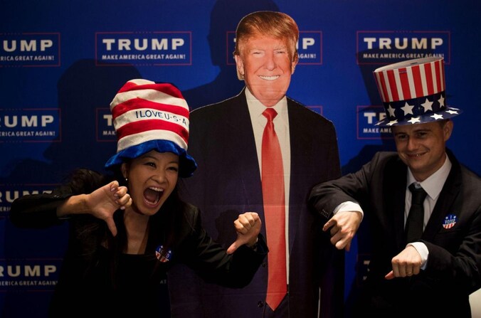Een koppel poseert voor een kartonnen Donald Trump tijdens een verkiezingsevenement dat het Amerikaanse consulaat in Shangai organiseerde.