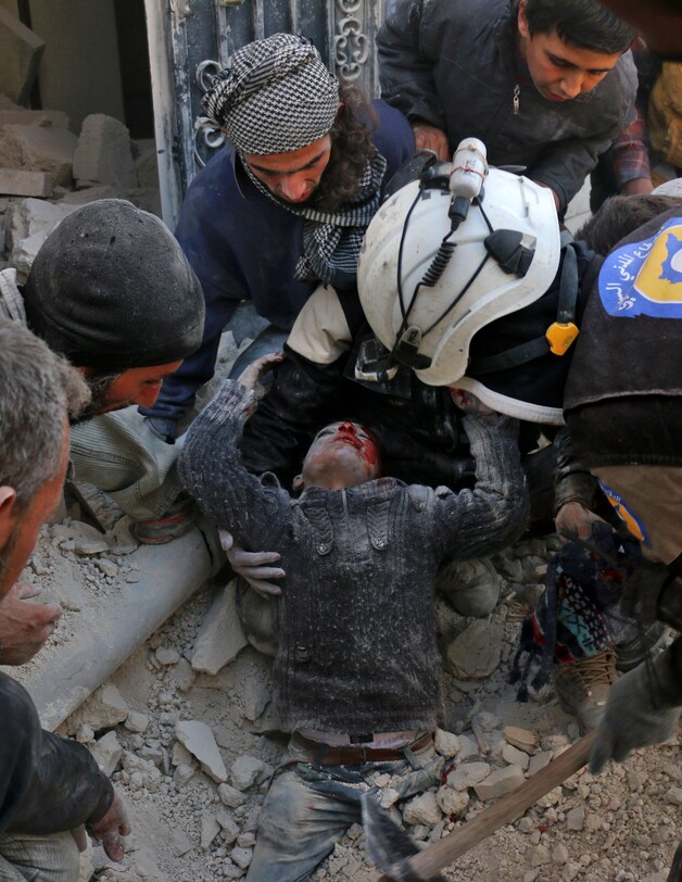 Vrijwilligers redden een jongen uit het puin in Aleppo.
