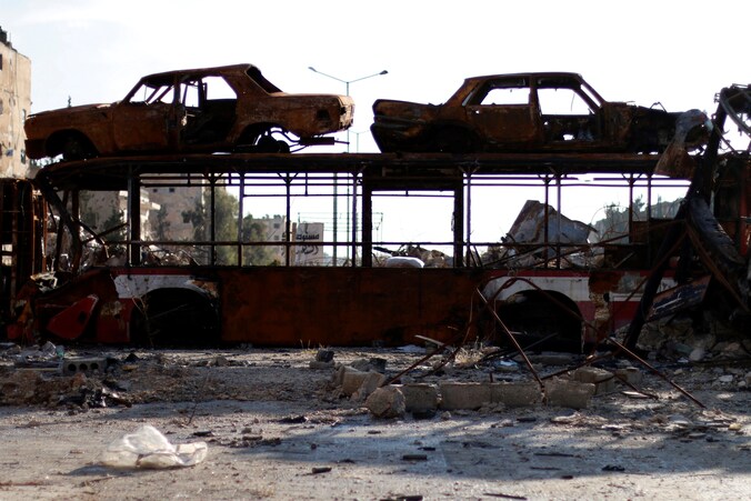 Een uitgebrande bus en auto's worden gebruikt als barricade, nadat regeringstroepen een deel van Aleppo hebben heroverd.