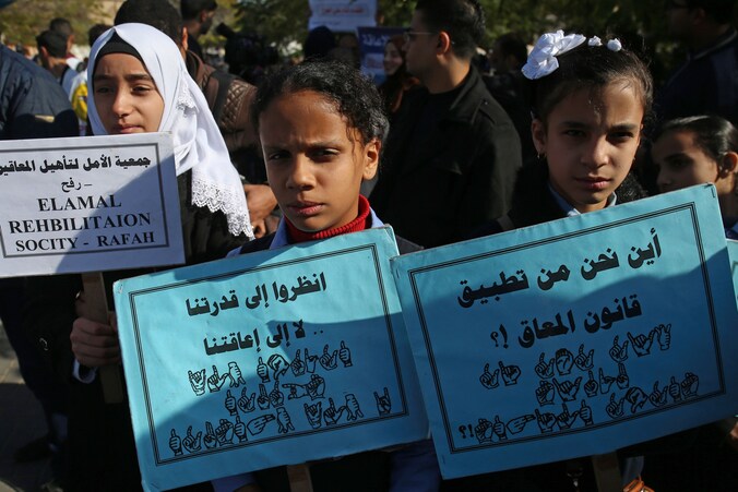 Palestijnse kinderen met een handicap houden bordjes omhoog in Gaza City waarbij ze rechten eisen voor mensen met een handicap.