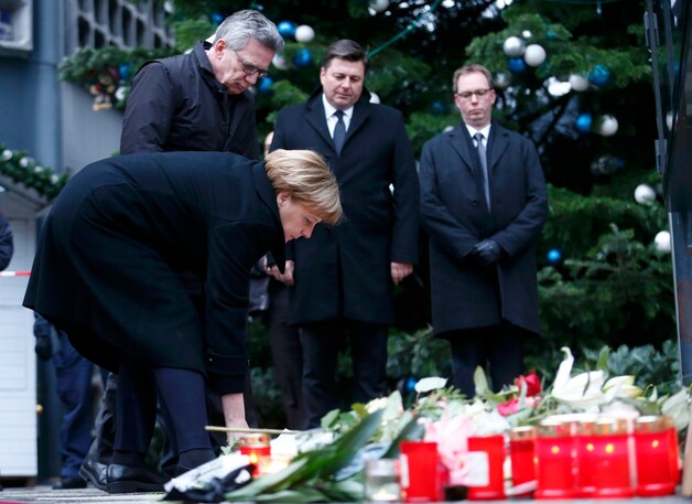 Angela Merkel legt een witte roos op de plek van de aanslag.