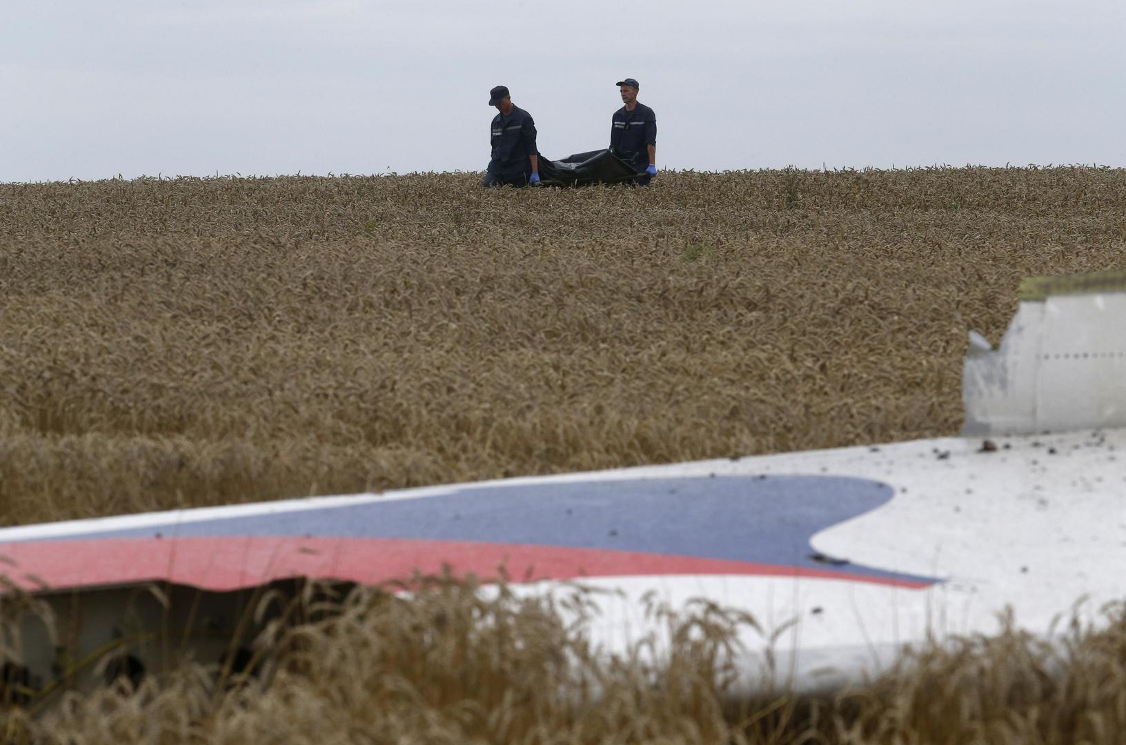 Leden van het Oekraïense 'Emergency Ministry' dragen de stoffelijke resten weg nabij de rampplek van MH17.
