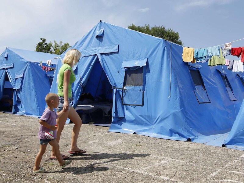 Een moeder en kind lopen door een tijdelijk vluchtelingenkamp in Oost-Oekraïne