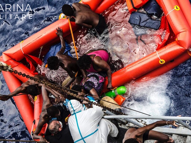 Reddingswerkers helpen migranten aan boord van het Italiaanse marineschip Vega.