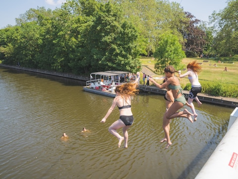 Jongeren springen van de fietsbrug aan het Keizerpark in Gent.