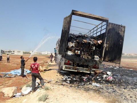 Mannen blussen een brandje in een vrachtwagen nadat die in brand vloog na een luchtaanval in de door rebellen gecontroleerde stad Atareb in de provincie Aleppo.