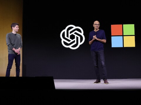 De bazen van OpenAI en Microsoft samen op het podium van een persconferentie.