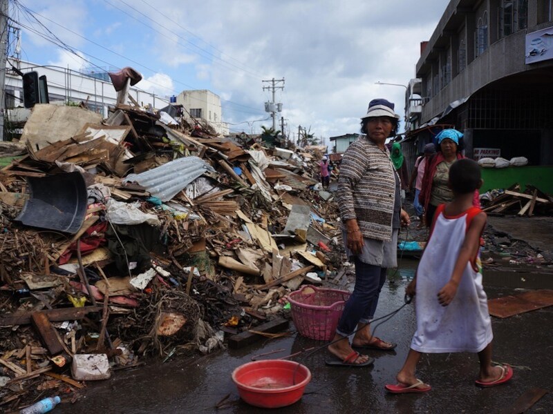Inwoners van Tacloban lopen langs de puinhopen van tyfoon Haiyan.
