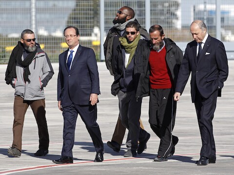 De Franse president en dienst minister van Buitenlandse Zaken samen met de vier vrijgelaten gijzelaars op de militaire luchthaven Villacoublay, buiten Parijs.