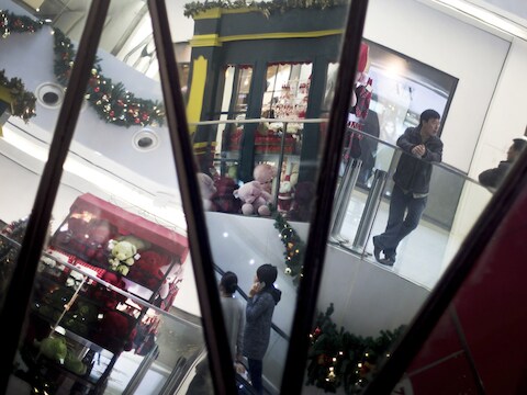 Shoppers zijn te zien in de spiegels van een winkelcentrum in Peking.