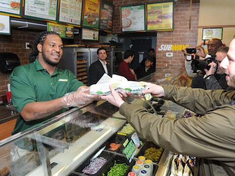 Een man krijgt een broodje bij Subway.