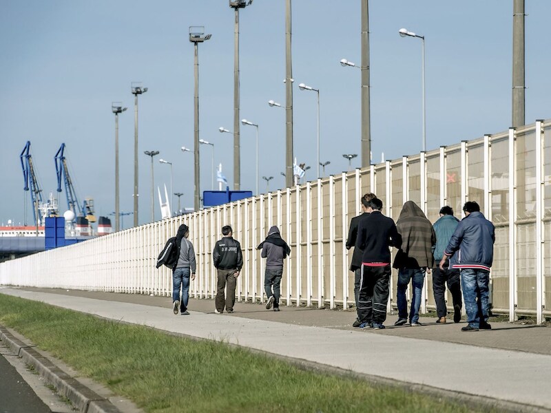 Migranten wandelen in de haven van Calais.