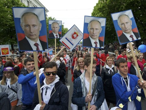 Demonstranten lopen met foto's van de Russische president Vladimir Poetin door Simferopol, de hoofdstad van de Krim.