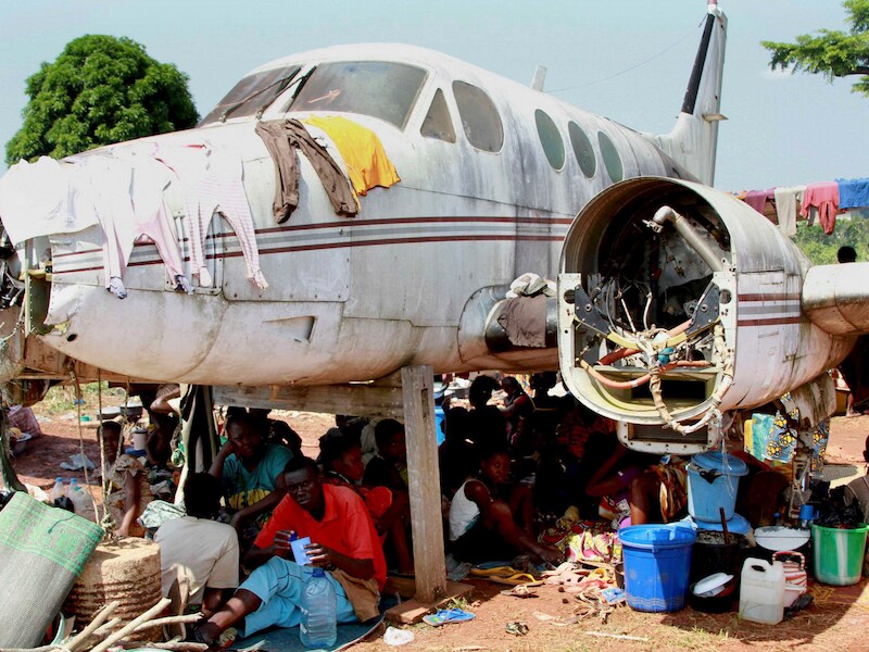 Vluchtelingen schuilen onder een vliegtuigwrak op de luchthaven van Bangui.