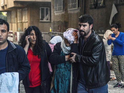 Inwoners van Diyarbakir begeleiden een vrouw die gewond is geraakt bij een explosie in de zuidoostelijke stad, waar ook parlementariërs zijn gearresteerd.