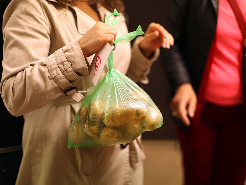 Een vrouw krijgt aardappelen tijdens een voedselbedeling van Caritas.