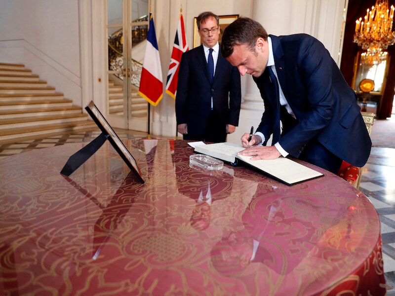 De Franse president Emmanuel Macron tekent in de Britse ambassade in Parijs het rouwregister voor de slachtoffers van de aanslag in Manchester.