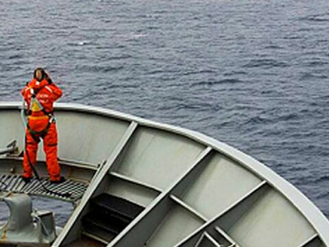 Een bemanningslid van de HMAS Success tuurt in het zuiden van de Indische Oceaan naar brokstukken van vlucht MH370