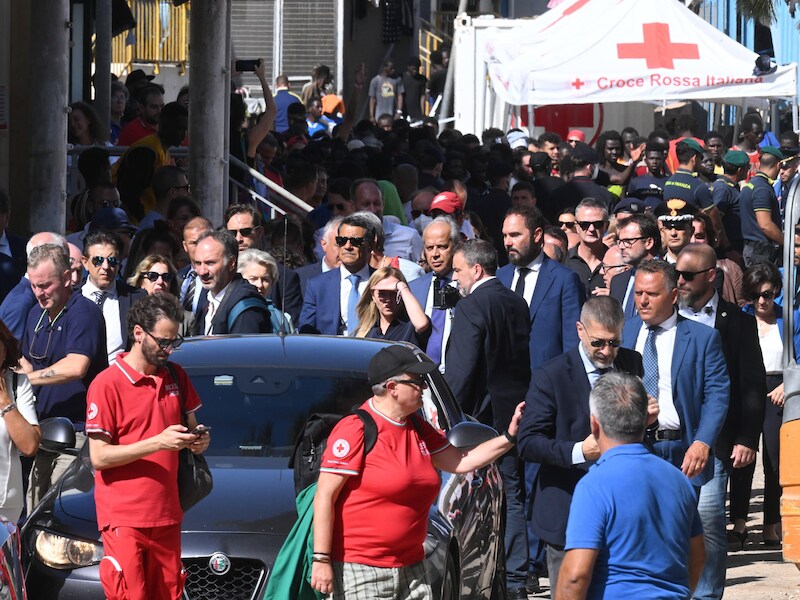 De Italiaanse premier Giorgia Meloni (achter de auto rechts), EU-voorzitter Ursula von der Leyen (links) en de Italiaanse minister Matteo Piantedosi verlaten zondagmorgen het vluchtelingenkamp op Lampedusa.