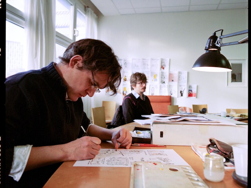 Laurent Sourisseau (Riss) (links) aan het werk op de redactie van Charlie Hebdo. Foto uit 2012.