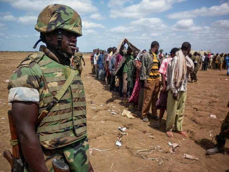 Een Oegandese soldaat van de Afrikaanse Unie bewaakt leden van al-Shabaab die zich hebben overgegeven.