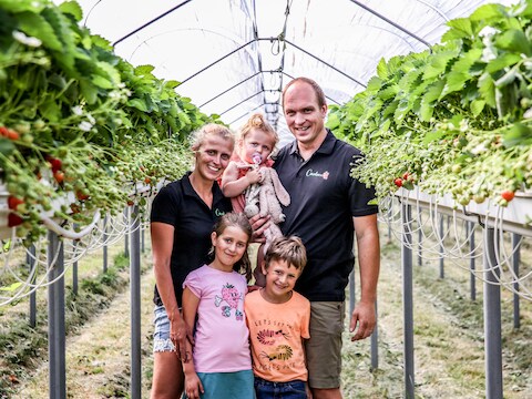 Sien en Dieter en de kinderen tussen de aardbeien, waar zondag de FrezeRun wordt gelopen. 