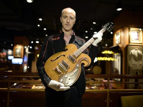 Een medewerker van het veilinghuis met de Beatles-gitaar.