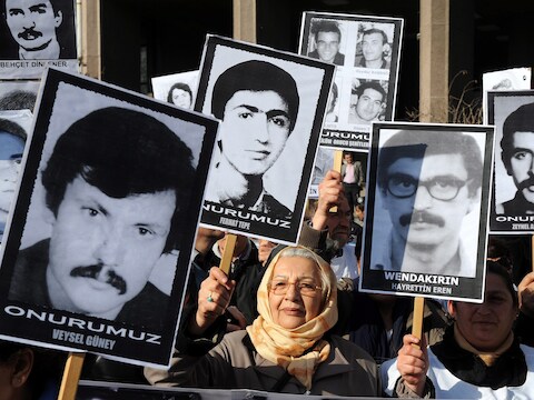 Turkse demonstranten houden portretten omhoog van mensen die tijdens de militaire dictatuur zijn geëxecuteerd.