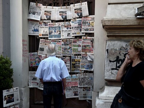 Een man bekijkt de voorpagina's van Griekse kranten in een kiosk in Athene.