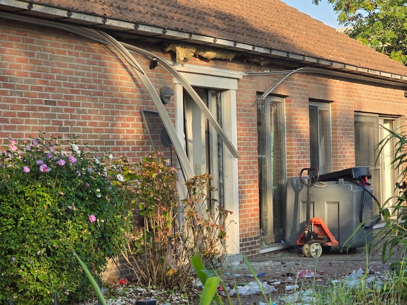 De voordeur van de woning in Lokeren raakte zwaar beschadigd door de ontploffing.