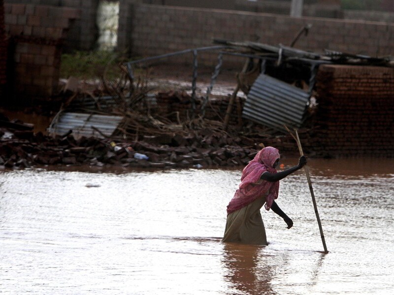 Een vrouw waadt door het water in Khartoem.