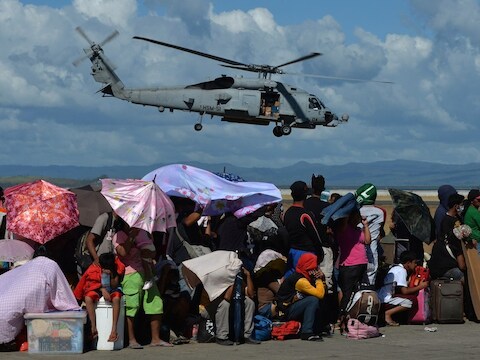 Slachtoffers van de tyfoon Haiyan wachten op het vliegveld van Tacloban op een vlucht om de zwaar beschadigde stad te ontvluchten.