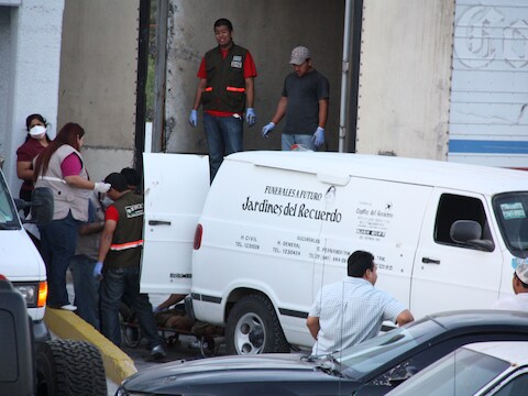 Forensische werkers dragen de lichamen weg van het massagraf. Meer foto's zijn er momenteel niet.