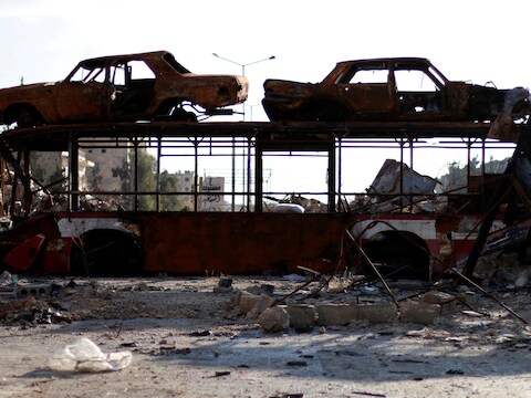 Een uitgebrande bus en auto's worden gebruikt als barricade, nadat regeringstroepen een deel van Aleppo hebben heroverd.