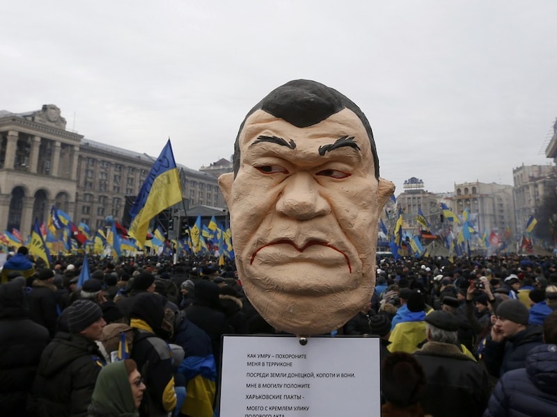Een beeld van de president van Oekraïne tussen de demonstranten in Kiev.