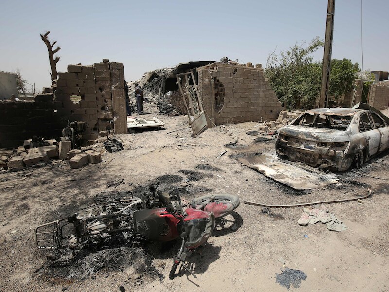 Beschadigde voertuigen en gebouwen in Fallujah na een gewelddadige confrontatie tussen IS-militanten en pro-regeringstroepen.