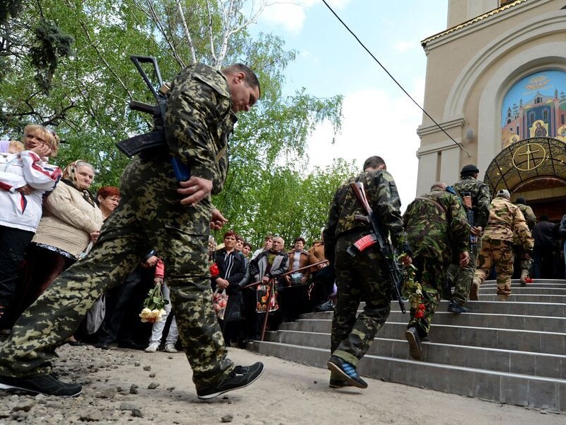 Gewapende mannen in camouflagepakken, vandaag bij een herdenkingsdienst voor eerder omgekomen mannen in Slavjansk.