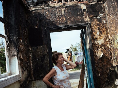 Een vrouw in Slavjansk bekijkt de schade aan haar huis nadat het werd getroffen in het spervuur tussen Oekraïense soldaten en Russische seperatisten.