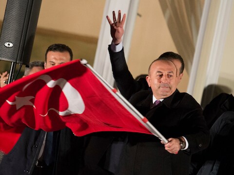 De Turkse minister van Buitenlandse Zaken Mevluet Cavusoglu, zwaaite met een Turkse vlag terwijl hij zijn aanhangers in Hamburg toewuift.
