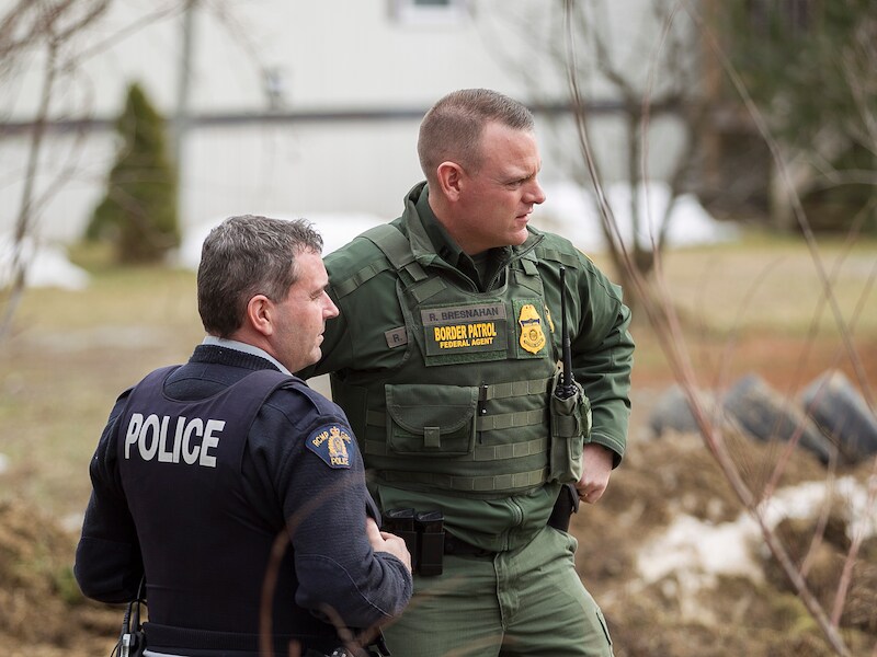 Een agent van de Amerikaanse grenspolitie (links) spreekt met een Canadese grenswacht in de Canadese staat Manitoba.